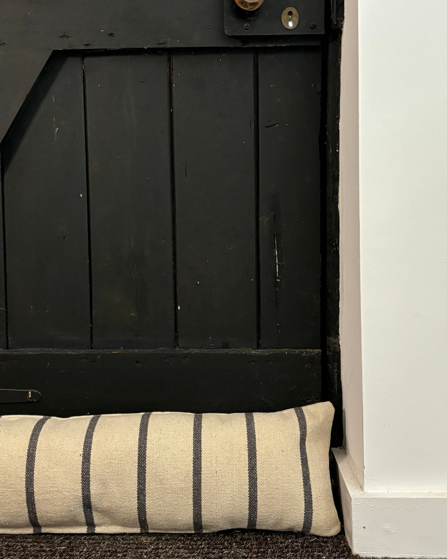Black wooden cabinet with a striped cushion on a white background
