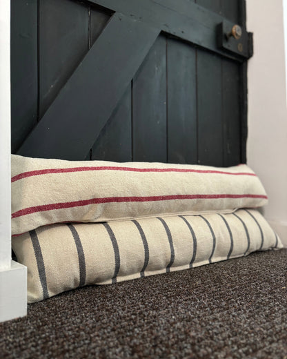 Two striped pillows stacked against a dark wooden door.