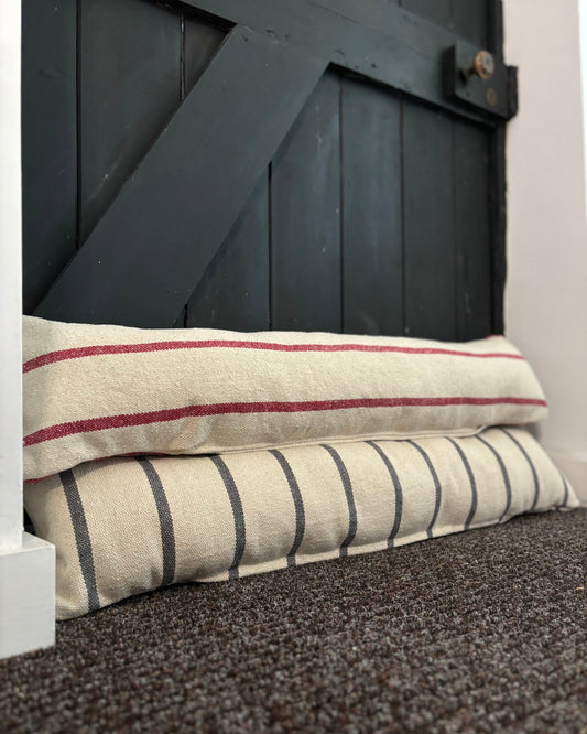 Two striped pillows stacked against a dark wooden door.